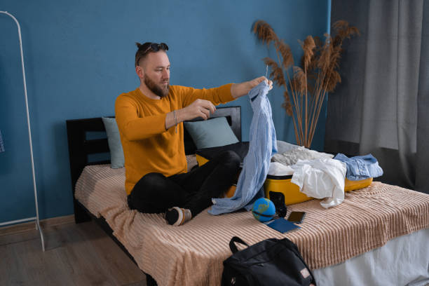 istock Man packing his clothes in suitcase at home. Travel concept. 1485341404