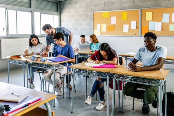 istock Male teacher helping students in classroom 1485343106