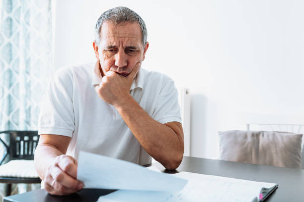 istock middle-aged man at table at home reading bill or letter 1485344365