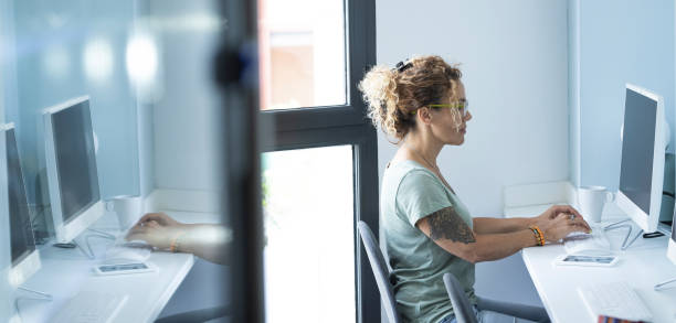 istock One young modern woman working on computer sitting at the desk in office bright corporate workplace. Tattoo. Professional new normal entrepreneur home work lifestyle. Mirrored and copy space concept 1485344759