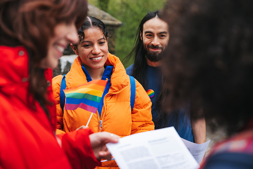 Multicultural group of LGBTQIA+ volunteers in New York City streets approaching people and let them sign up. Equal rights and gender stereotypes awareness.