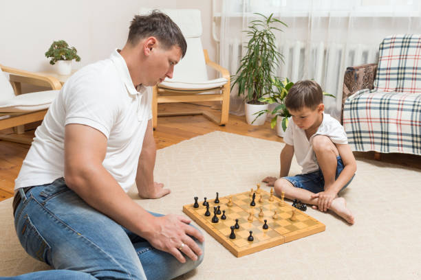 屋内でチェスをする父と息子の白人の家族。 - family with one child family two parent family father ストックフォトと画像
