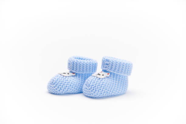 A pair of handmade blue knitted baby booties, isolated on white background. Newborn clothing and pregnancy. Fashion stock photo