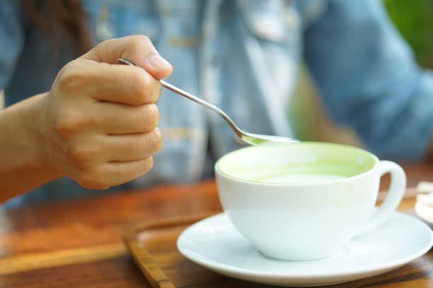 istock Woman using spoon to scoop hot green tea 1485351996