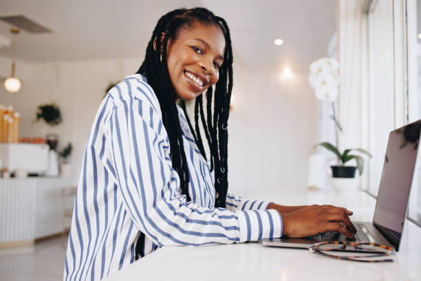 istock Cheerful female freelancer smiling at the camera while typing on a laptop in a cafe 1485353189
