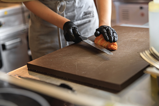 The cook is preparing the croissant with the filling in restaurant kitchen. High quality photo