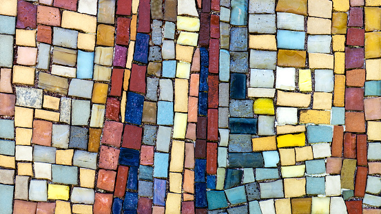 Detail of a colorful, very old mosaic of square little pieces on a weathered wall
