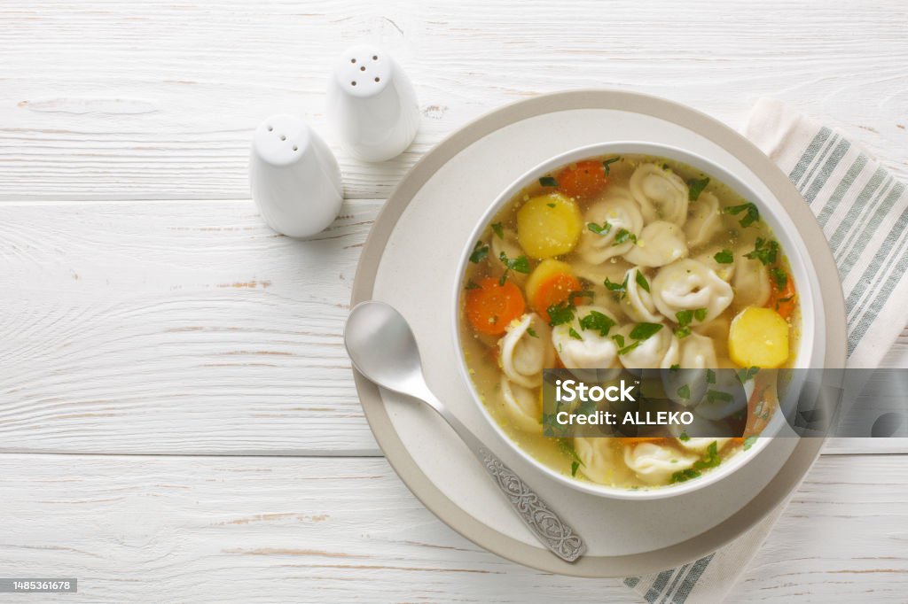 Soup with pelmeni dumplings a dish of Russian cuisine closeup on the bowl. Horizontal top view Soup with pelmeni dumplings a dish of Russian cuisine closeup on the bowl on the wooden table. Horizontal top view from above Chicken Meat Stock Photo