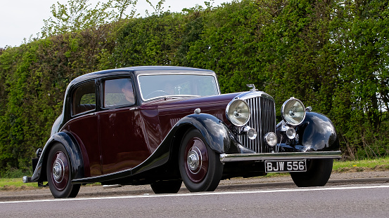 Bicester,Oxon,UK - April 23rd 2023.  1936 maroon Bentley 4¼ litre Saloon by Park Ward, one of only 12 built with this style of bodywork, travelling on an English country road