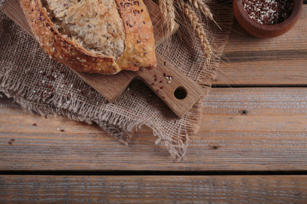 Fresh baked whole grain bread with oats, flax seeds and sesame seeds on rustic wooden board. Bakery products