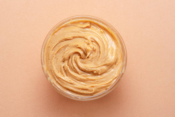 istock Bowl of peanut butter on beige background. Top view. 1485364011