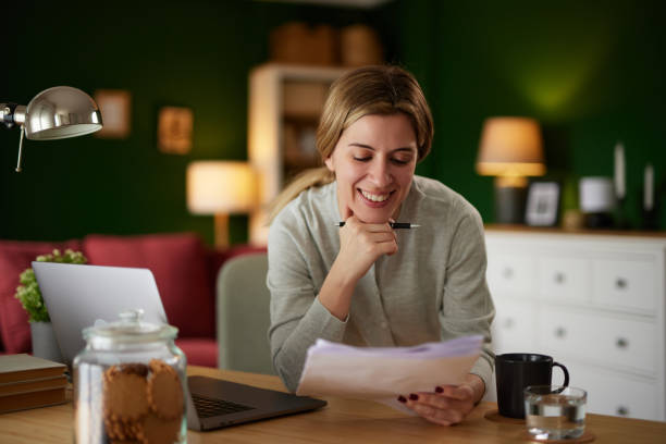 istock Smiling woman examining her bank statement at home office 1485365782