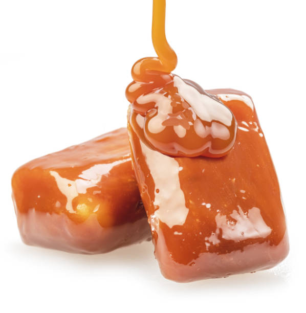 istock Caramel candies covered with melt caramel isolated on white background. 1485369101