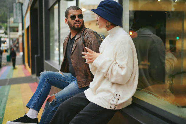 istock Two friends talking while sitting on a sidewalk painted in the pride colors 1485373515