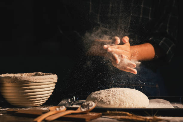 istock Professional baker woman slaps flour over the dough while making sourdough or artisan bread on the table in the kitchen. Small business homemade bakery at home. 1485373705