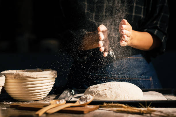 istock Professional baker woman slaps flour over the dough while making sourdough or artisan bread on the table in the kitchen. Small business homemade bakery at home. 1485373716