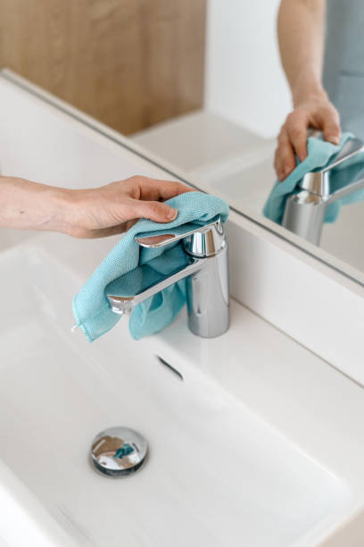 Cleaning water tap with a rag in the bathroom