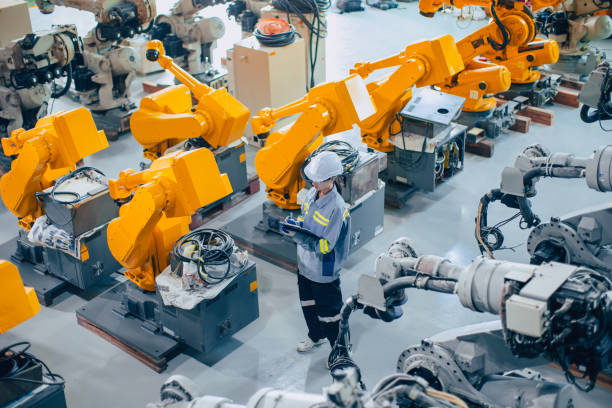 Engineer staff worker working in large machine assembly plant. employee work icounting inspection inventory of machine robot arm.