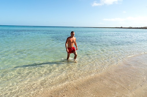 Attractive muscular athletic man in the ocean. Summer vacation. Sunny day. Tourism.