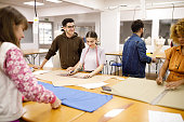 Fashion students measuring  and cutting fabrics during class