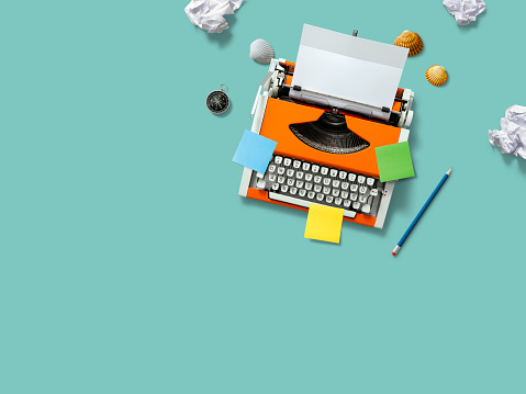 Orange typewriter with colorful notes and crumpled paper balls