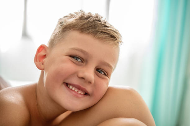 A cute toddler sits in a bathtub, displaying a cheerful expression with a playful gesture.
