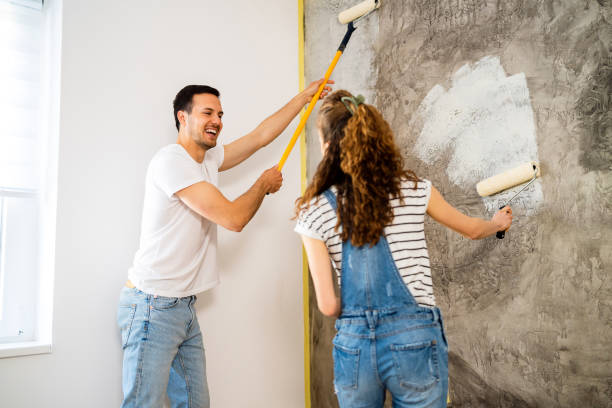 pareja joven pintando la pared en un nuevo apartamento - home improvement couple painting real estate fotografías e imágenes de stock