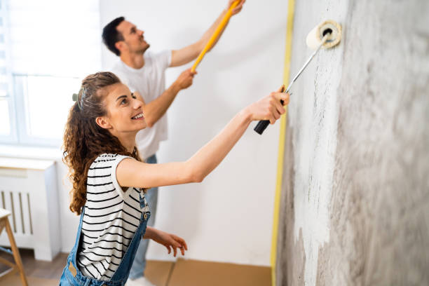 pareja pintando la pared en apartamento nuevo - home improvement couple painting real estate fotografías e imágenes de stock