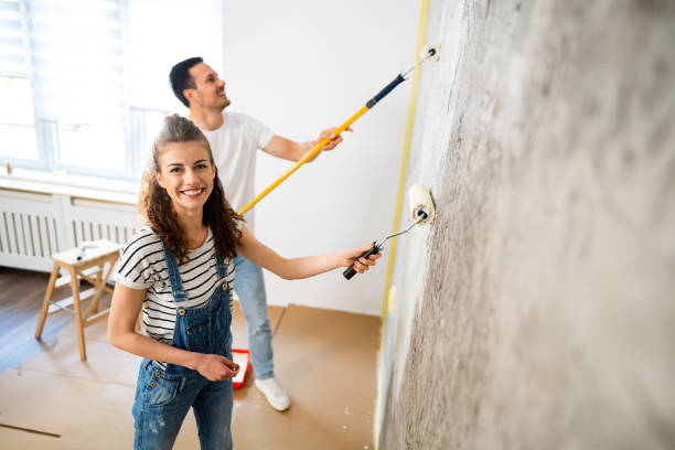 pareja caucásica pintando la pared en un nuevo apartamento - home improvement couple painting real estate fotografías e imágenes de stock