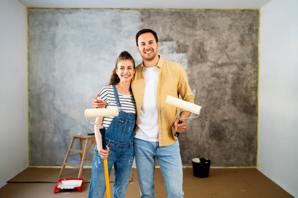 pareja caucásica, con un rodillo de pintura en sus manos, mientras renueva un nuevo apartamento - home improvement couple painting real estate fotografías e imágenes de stock