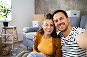 Couple, sitting on the floor in new apartment and taking selfie