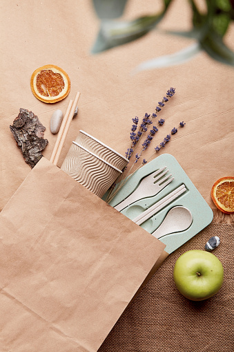 Eco shopping bag with cutlery, apples, lavender on crumpled paper mock up. Sustainable lifestyle. Natural eco-friendly, zero waste tableware, blurred foreground