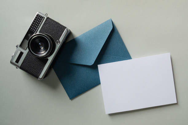 istock White blank greeting or invitation card and envelope with vintage camera on green background. Mock up presentation. 1485399690