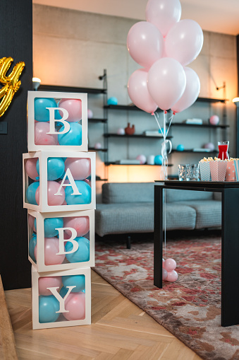 Interior of living-room in modern flat prepared for birthday party of little kids and decorated with balloons and flags