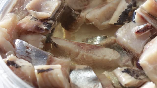 pieces of herring fillet in oil rotate in a circle