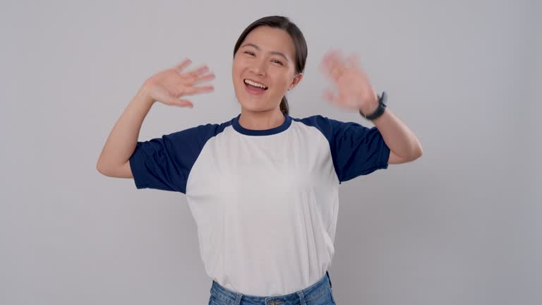 Asian woman happy smiling looking at camera waving hands gesturing hello or goodbye, isolated on background.