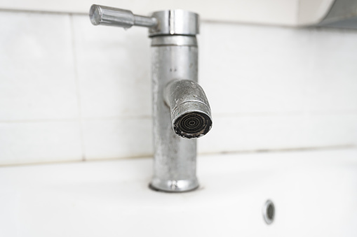 detail in modern bathroom interior. closeup view of chrome shower head on holder against tiled wall background with copy space in hotel or apartment
