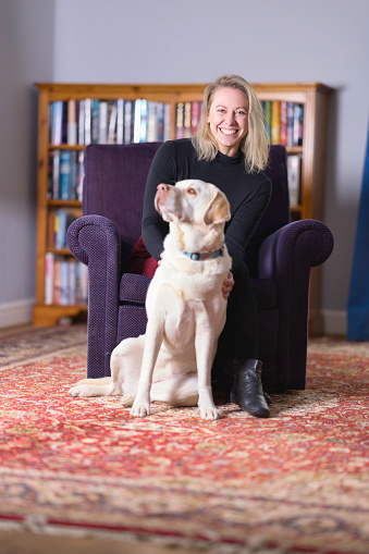 Dog hairs abound as the Yellow Labrador Retriever shoves her way in. Focus on lady.