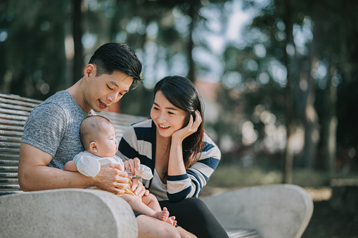 Asian Chinese Parents bonding with their baby boy in public park during weekend morning