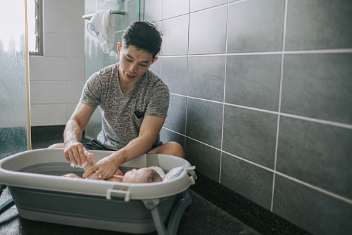 Asian Chinese father bathing baby boy in bathroom