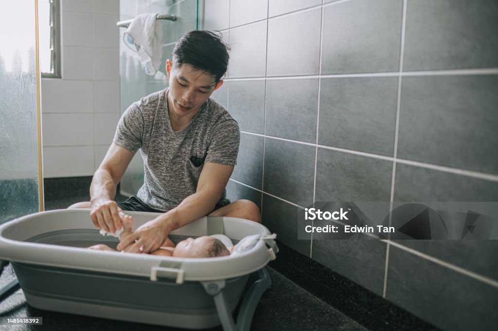 Asian Chinese father bathing baby boy in bathroom Asian and Indian Ethnicities Stock Photo