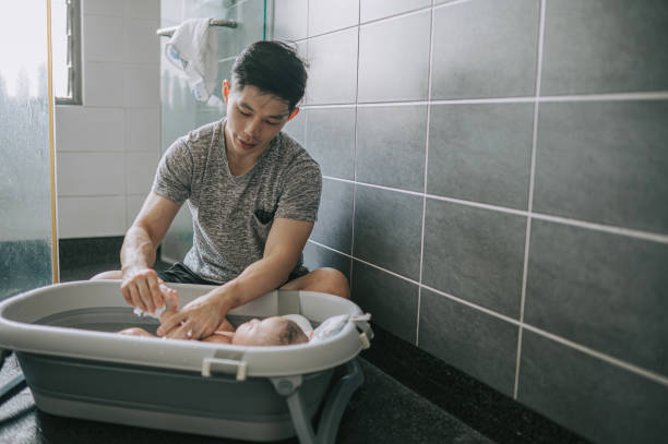 Asian Chinese father bathing baby boy in bathroom Asian Chinese father bathing baby boy in bathroom asian stay at home parent stock pictures, royalty-free photos & images