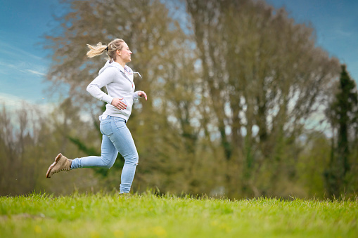 Lady in casual clothes running across a field.