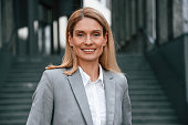 Woman in formal clothes is outdoors near the business building