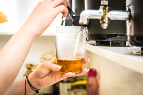 Pouring mixed tea from plastic jug to plastic shot, prepared for iced milk tea with bubble or boba. Selective focus.