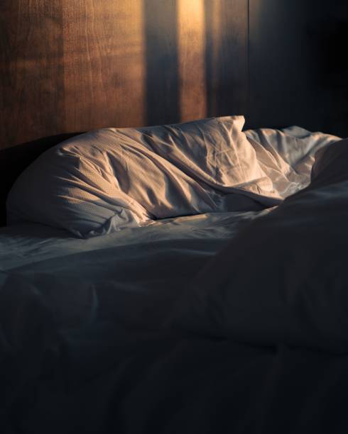 istock an unmade bed in a dimly lit room with a light shining on it 1485427605