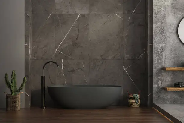 Photo of A modern bathroom featuring an anthracite bathtub, marble ceramic tiles on the back wall, parquet flooring, plants and a basket. 3d rendering