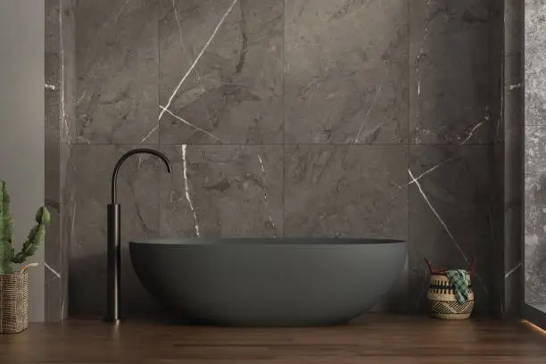 Photo of A modern bathroom featuring an anthracite bathtub, marble ceramic tiles on the back wall, parquet flooring, plants and a basket. 3d rendering