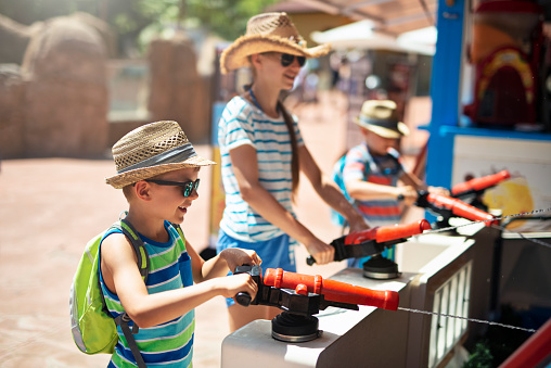 Kids having fun in a water cannons in amusement park. 
Nikon D810