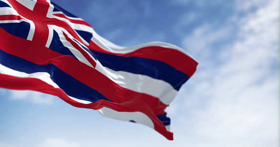 The flag of Hawaii waving in the wind on a clear day. Eight horizontal stripes white, red, blue, Union Jack in canton. 3d illustration render. Selective focus. Fluttering fabric
